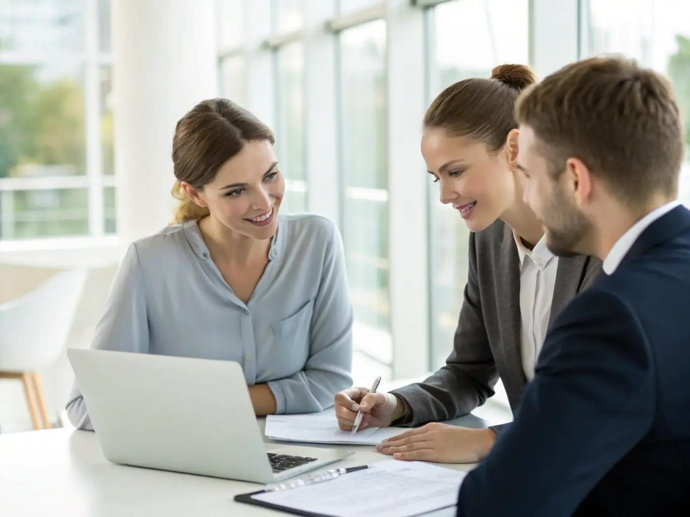 An image of a business consultant discussing strategies with clients over documents and a laptop.